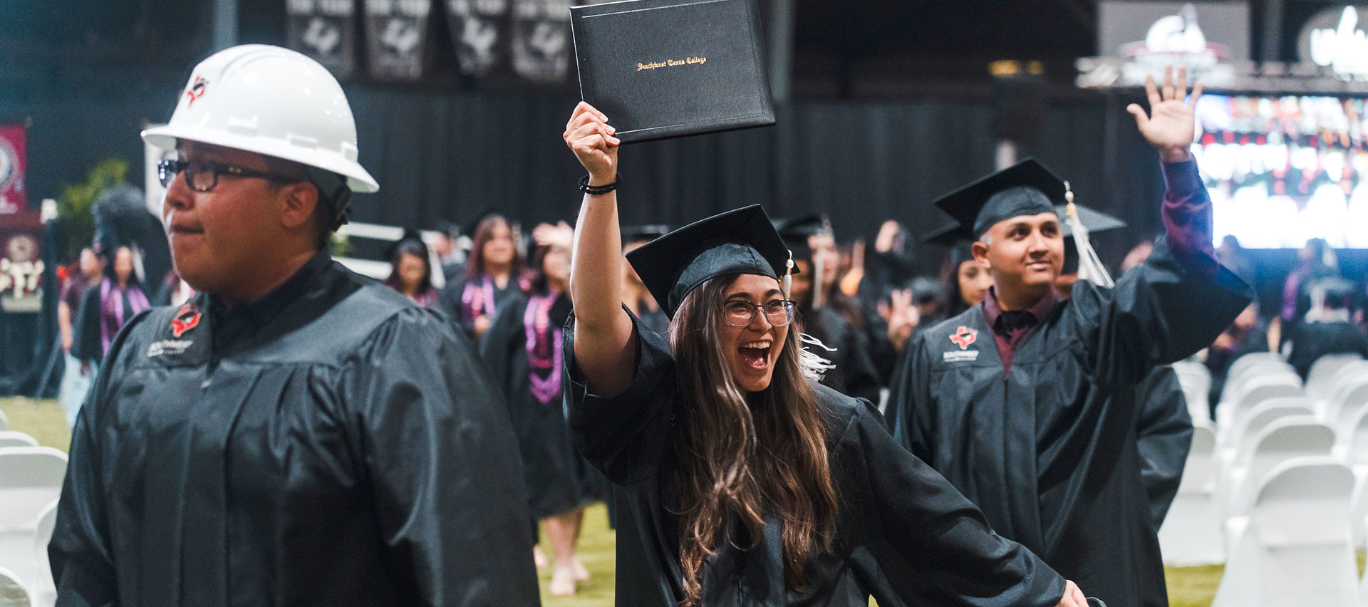 Three 2025 SWTX graduates celebrate in their cap and gown regalia.