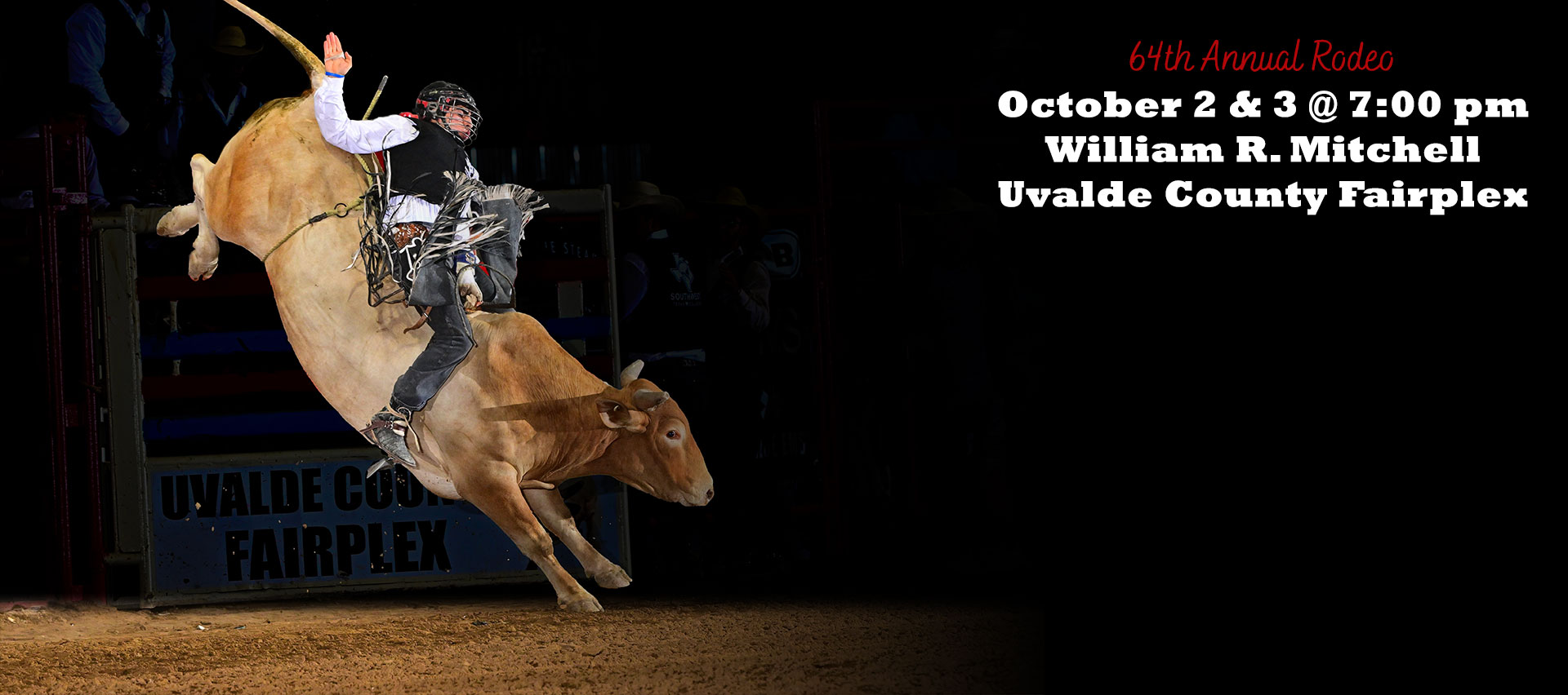 A rodeo bull rider rides a brown bull under a spotlight in a dark arena. To the right, the words 64th Annual Rodeo, October 2nd and 3rd at 7:00 pm at the William R. Mitchell Uvalde County Fairplex.