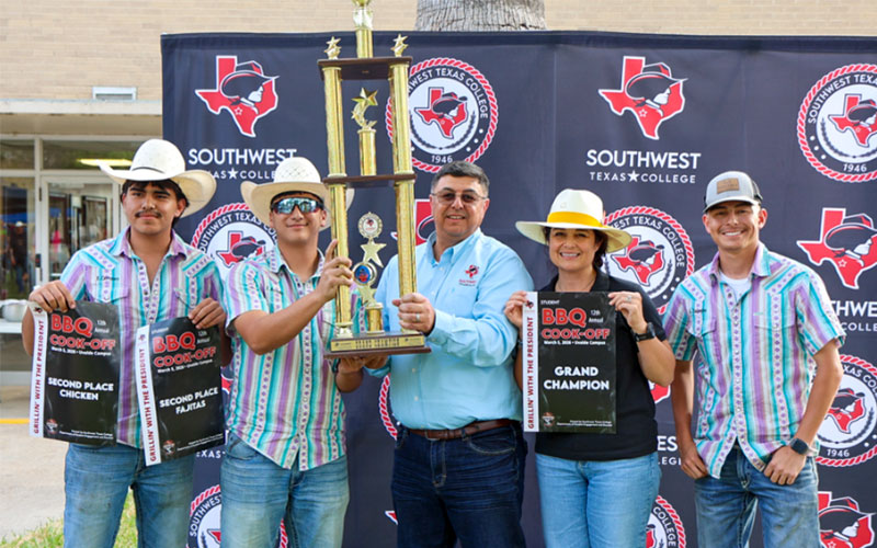 Dual Credit Welding Teams pose alongside SWTX President, Dr. Hector Gonzales and wife Jaclyn, with the Grand Champion trophy and various banners.