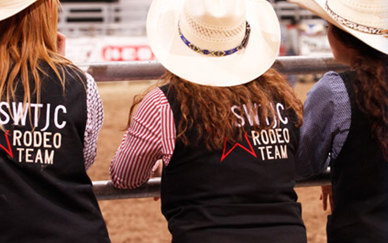 People watching the rodeo from the fence